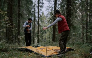 A family setting up a camping tent in a forest