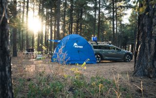 A dome camping tent set up in a lush green forest